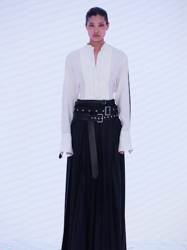 A model wearing a white shirt and black long Peter Do skirt